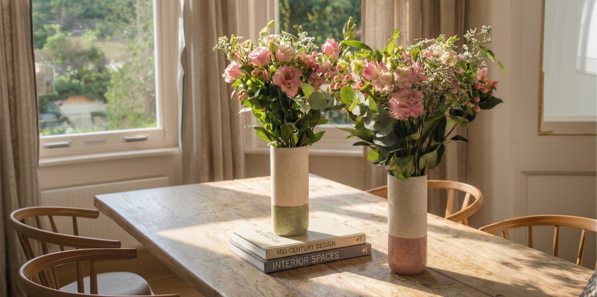 Ein Strauß aus weißen Rosen, kleinen rosafarbenen Blumen und zartem Grün, arrangiert in einer Vase, gebadet in warmem Sonnenlicht auf einer hölzernen Oberfläche.