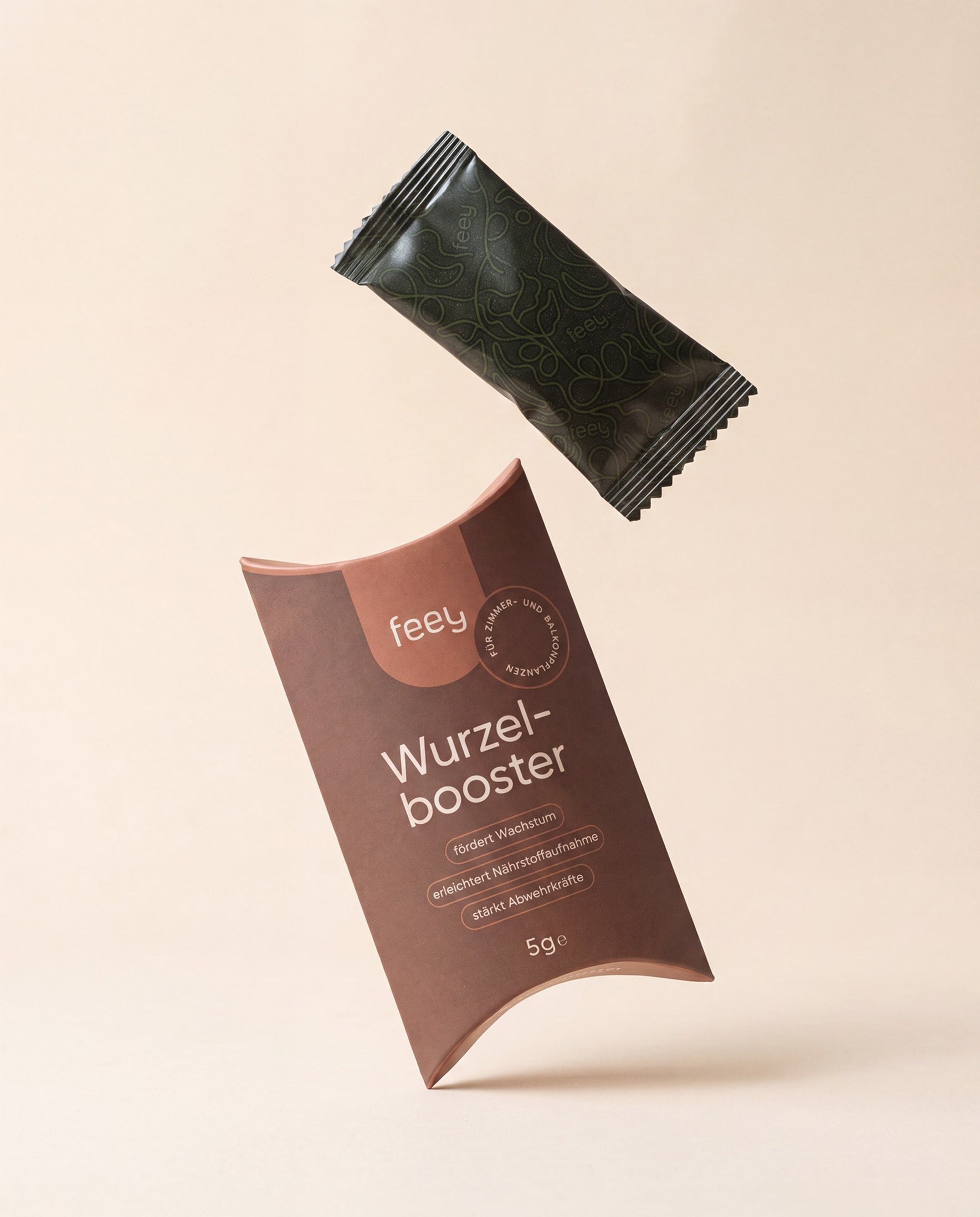 feey Wurzelbooster 5g Verpackung mit einem schwebenden dunkelgrünen Sachet vor cremefarbenem Hintergrund