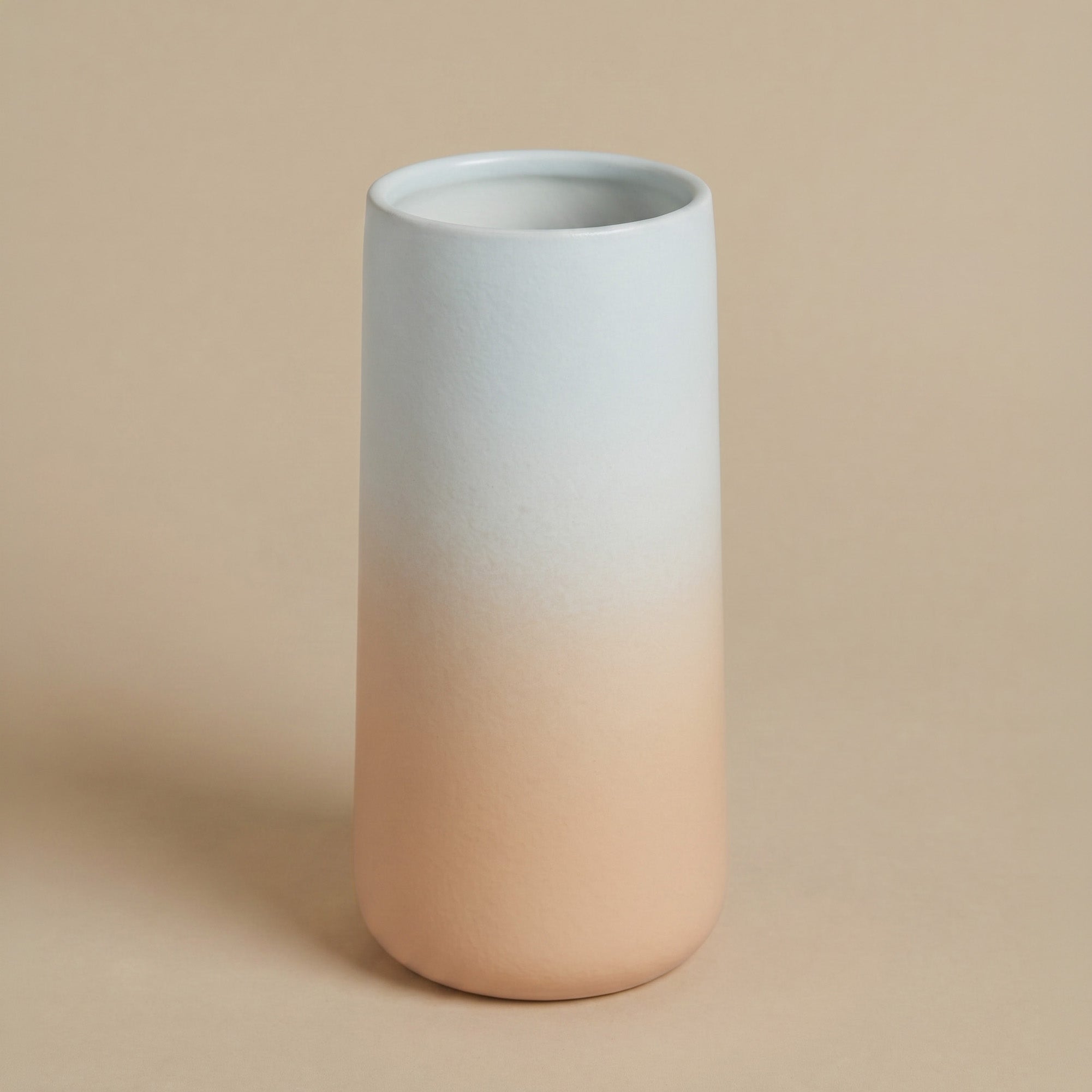 Einzelne feey Keramik-Vase 'Solio' mit Farbverlauf von Hellblau zu Pfirsich, freigestellt auf beigem Hintergrund